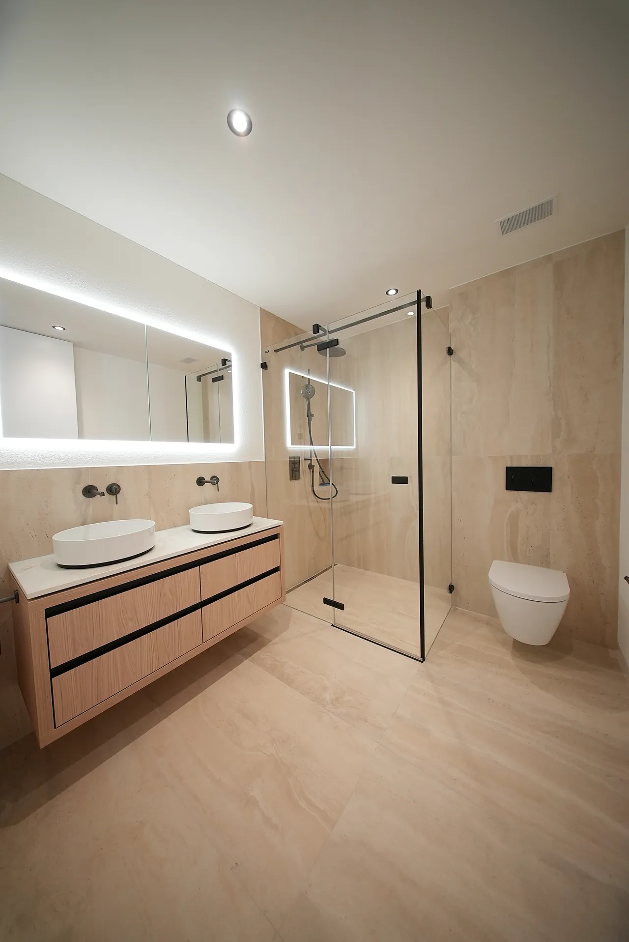 Badezimmer mit bodenebener Dusche, Glaswand, wandhängendem WC und Doppelwaschtisch