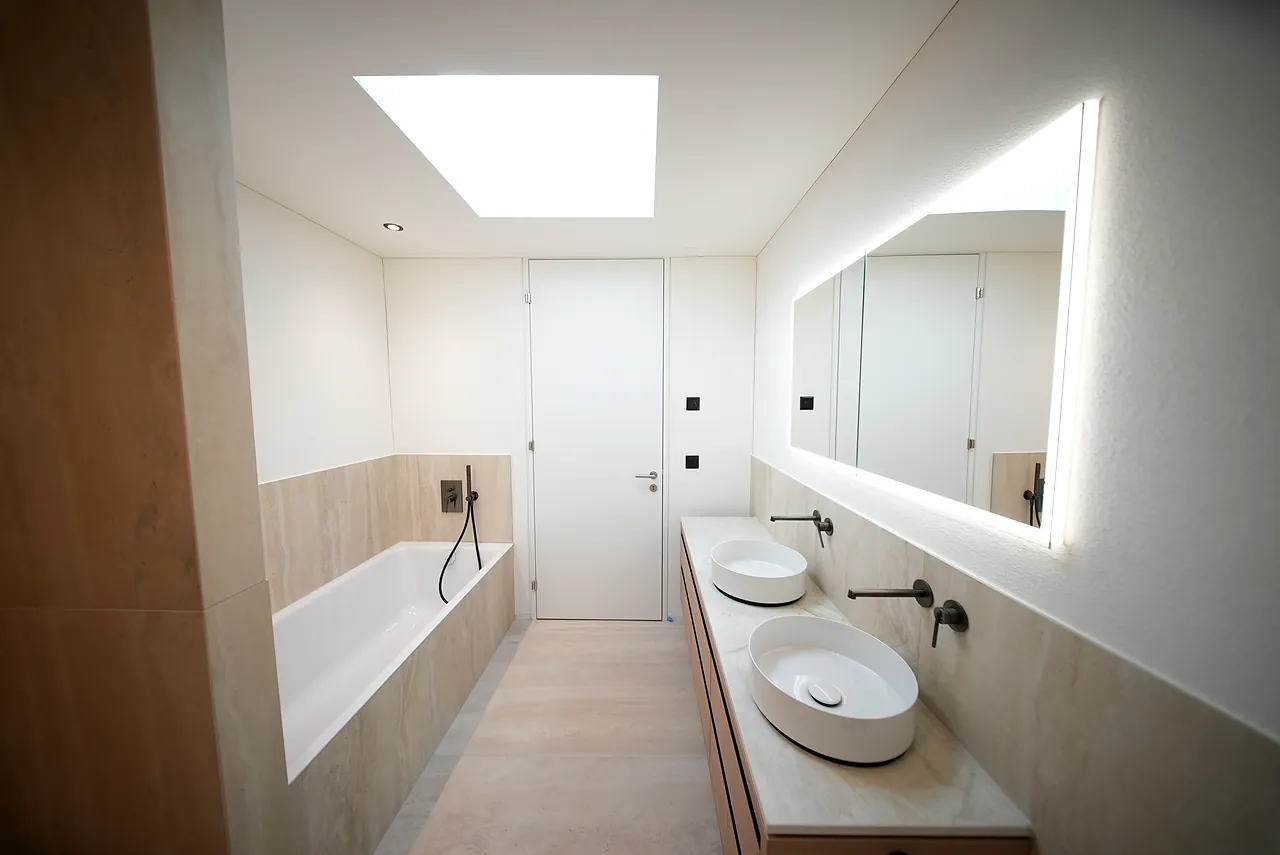Langes Badezimmer mit Oberlicht, Badewanne und Waschtisch