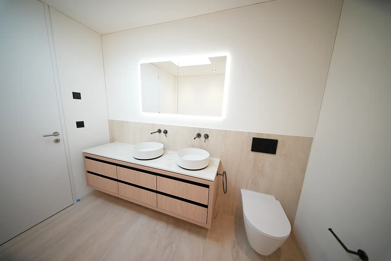 Badezimmer mit wandhängendem WC und Doppelwaschtisch mit zwei Aufsatzbecken