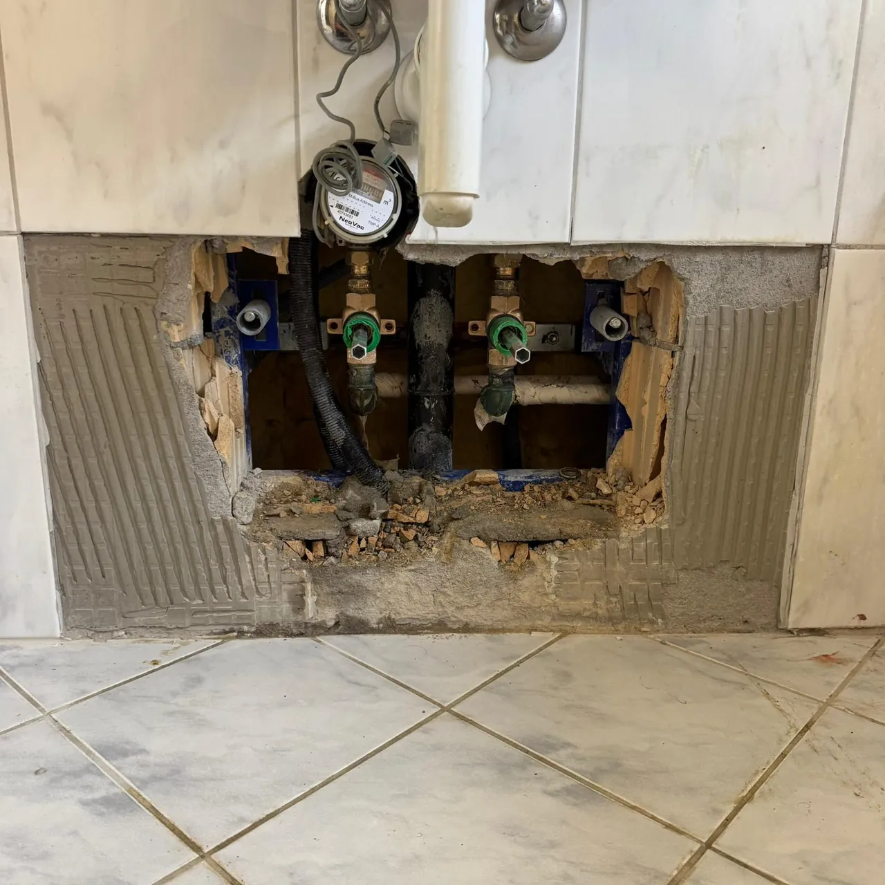 Gezielt geöffnete Wand unter dem Lavabo mit Absperrventilen und Wasserzähler bei einer Reparatur