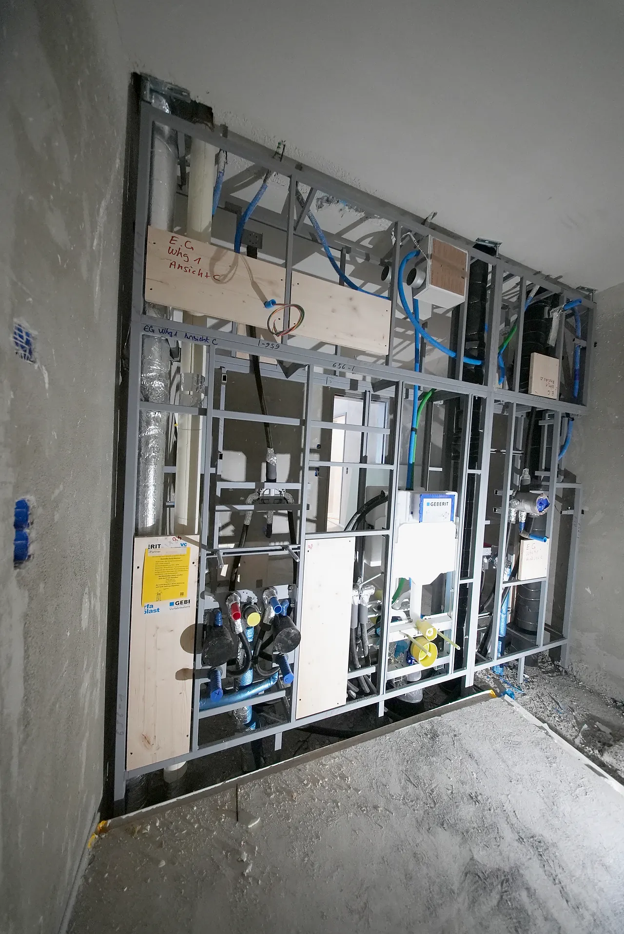 Installationswand mit Wasserleitungen und Abwasser im Rohbau eines Badezimmers