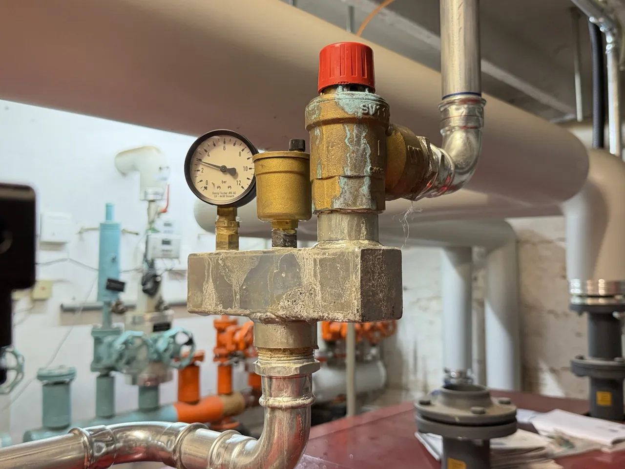 Sicherheitsgruppe mit Manometer und Kalk- und Korrosionsspuren in einer Heizzentrale