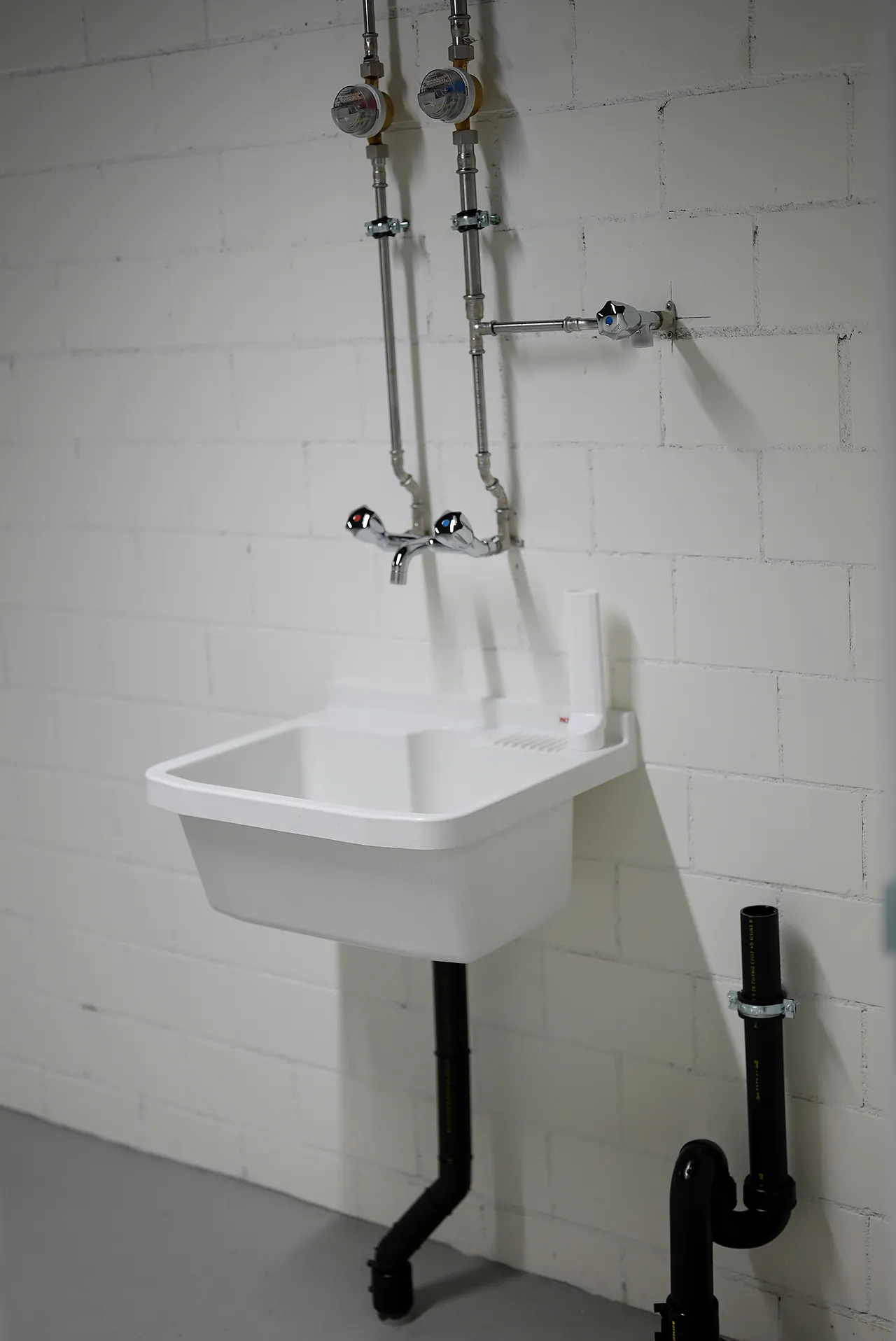 Zwei Wasserzähler mit Ausguss im Technikraum